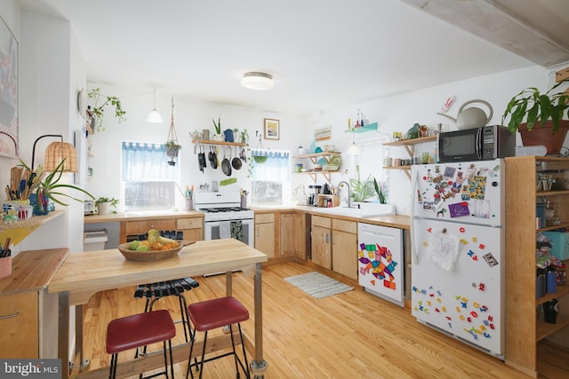 kitchen with white appliances, sink, light wood-type flooring, light brown cabinetry, and butcher block countertops