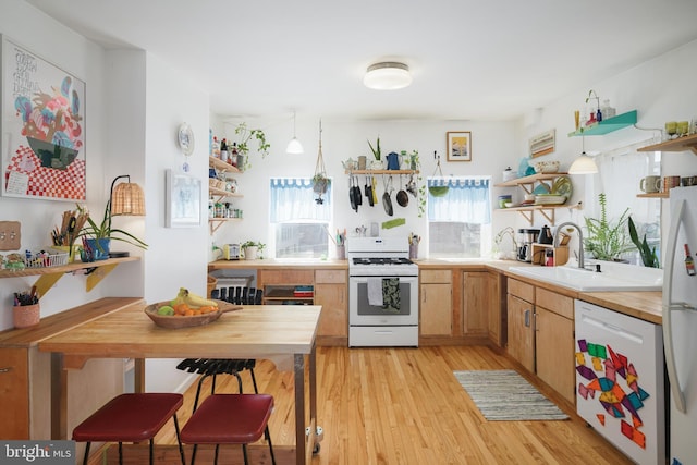 kitchen featuring sink, decorative light fixtures, white appliances, and light wood-type flooring