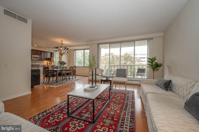 living room featuring a notable chandelier, a baseboard radiator, and light hardwood / wood-style floors