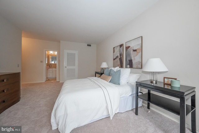 bedroom with connected bathroom and light colored carpet