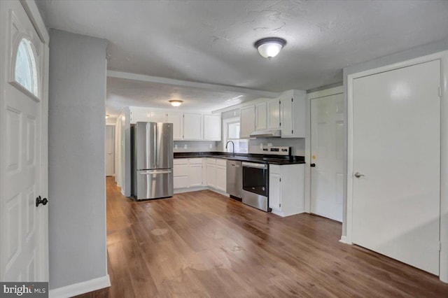 kitchen featuring dark hardwood / wood-style flooring, a textured ceiling, stainless steel appliances, sink, and white cabinets