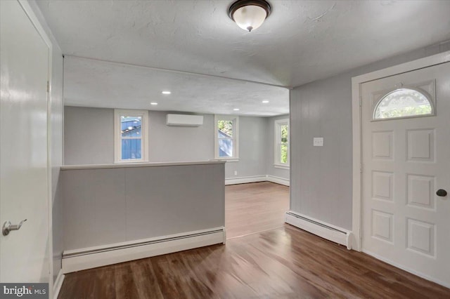 foyer featuring a wall mounted AC, wood-type flooring, and baseboard heating