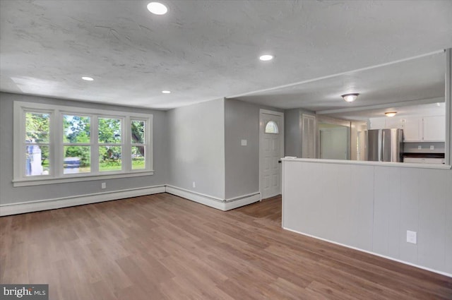 unfurnished living room featuring hardwood / wood-style floors and a baseboard heating unit