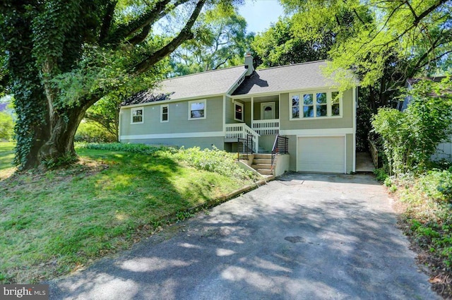 view of front of home featuring a front yard, a porch, and a garage