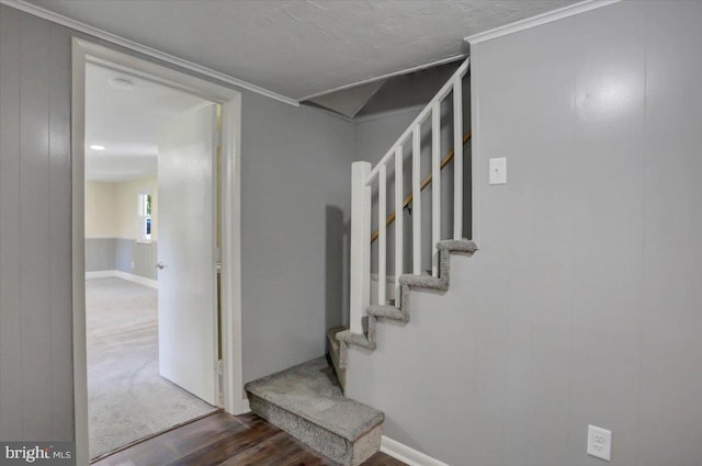 staircase with wood-type flooring and ornamental molding