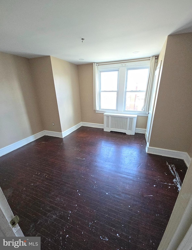 spare room featuring dark hardwood / wood-style floors and radiator