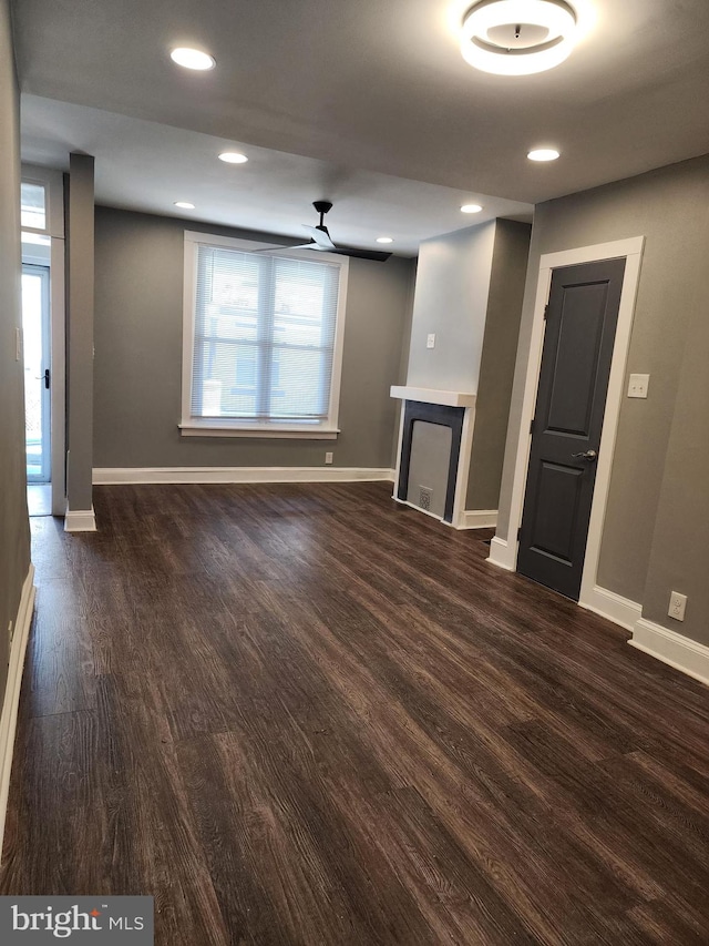 unfurnished living room featuring ceiling fan, a fireplace, and dark hardwood / wood-style flooring