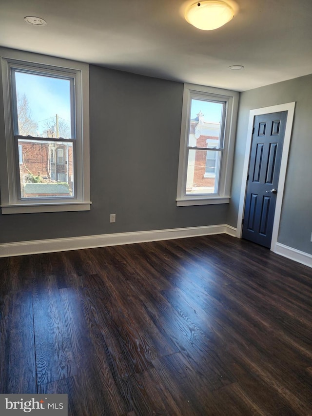 unfurnished room with a healthy amount of sunlight and dark wood-type flooring