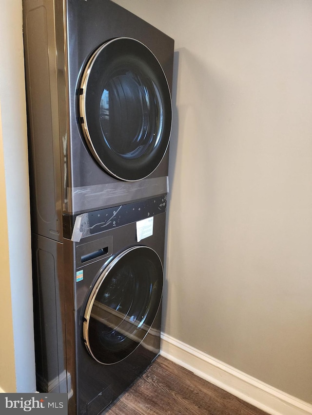 laundry area featuring dark wood-type flooring and stacked washing maching and dryer