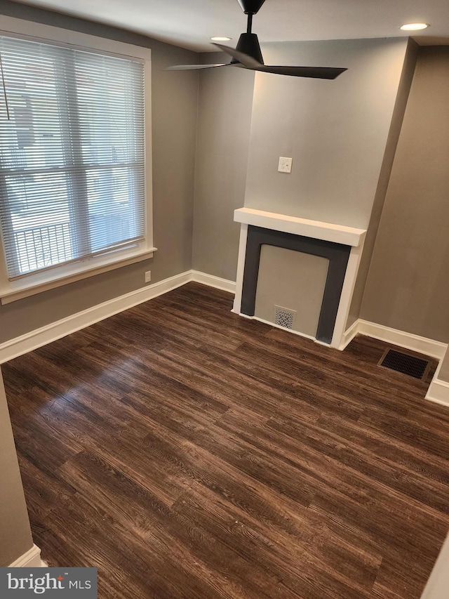 unfurnished living room featuring ceiling fan and dark wood-type flooring