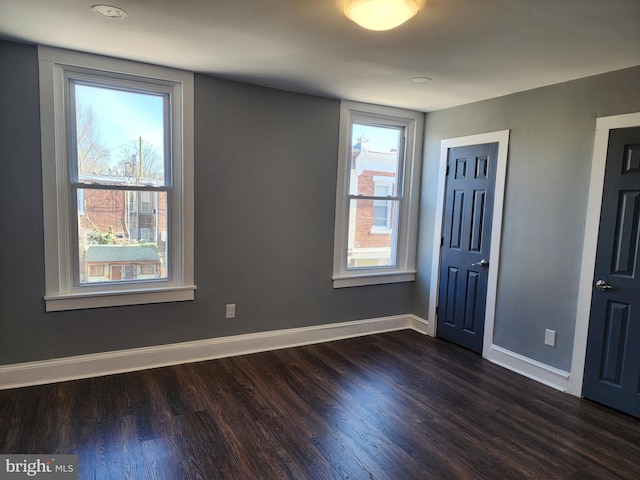 unfurnished bedroom with dark wood-type flooring and multiple windows