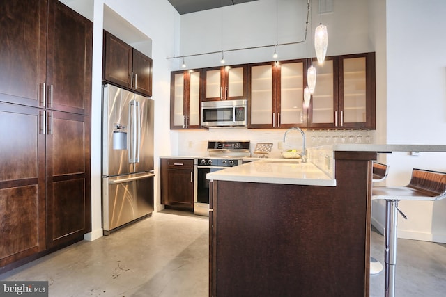 kitchen with sink, decorative light fixtures, a kitchen bar, kitchen peninsula, and stainless steel appliances