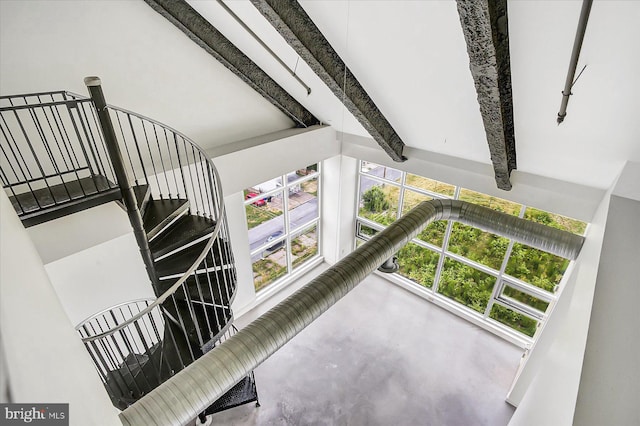 staircase featuring beam ceiling and concrete floors