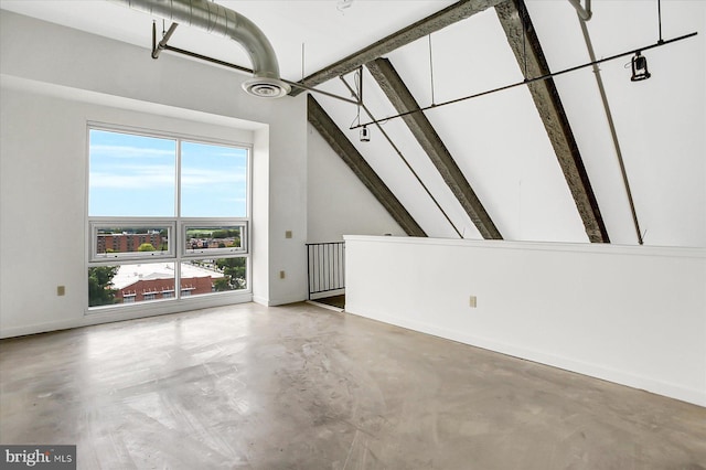 unfurnished living room with beamed ceiling, concrete flooring, and a towering ceiling