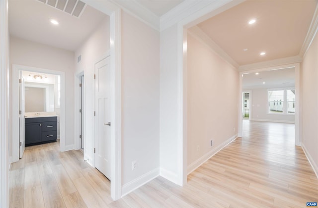 hall featuring light wood-type flooring, ornamental molding, and sink