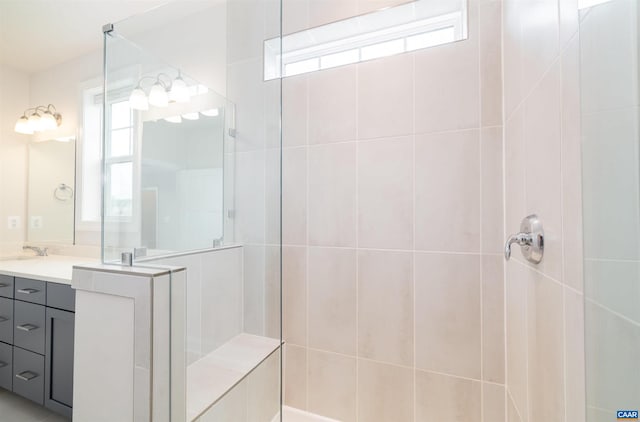 bathroom with a tile shower, vanity, and plenty of natural light