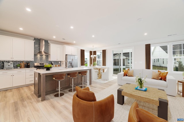 living room with a healthy amount of sunlight, crown molding, sink, and light hardwood / wood-style flooring