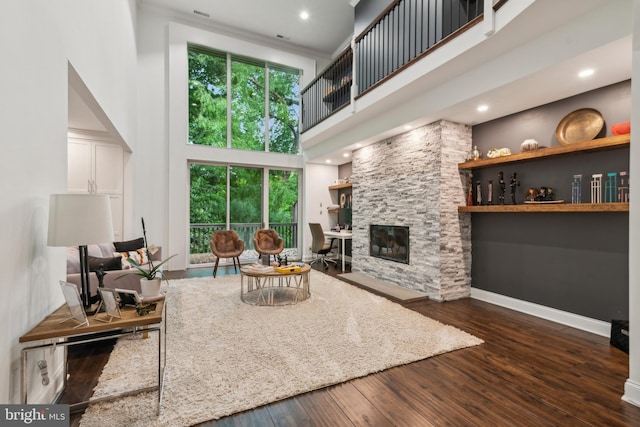 living room featuring a fireplace, dark hardwood / wood-style flooring, a healthy amount of sunlight, and a high ceiling