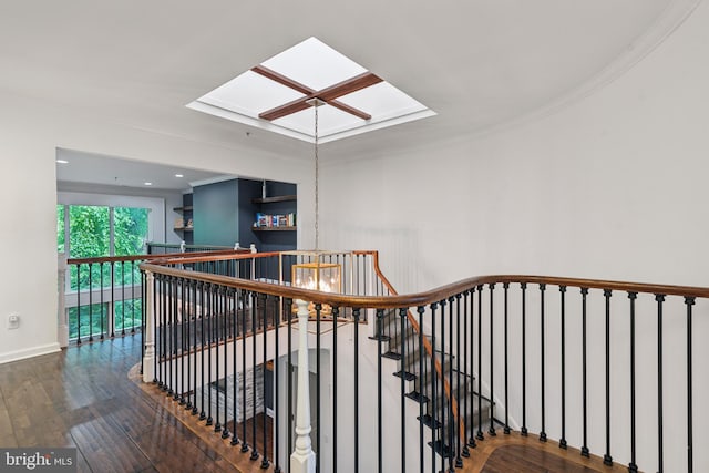 stairs featuring hardwood / wood-style flooring, crown molding, and a skylight