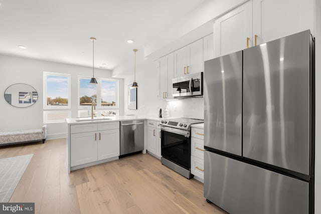 kitchen with white cabinetry, sink, stainless steel appliances, light hardwood / wood-style flooring, and pendant lighting