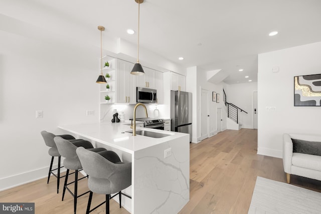 kitchen with a kitchen breakfast bar, kitchen peninsula, appliances with stainless steel finishes, decorative light fixtures, and white cabinetry