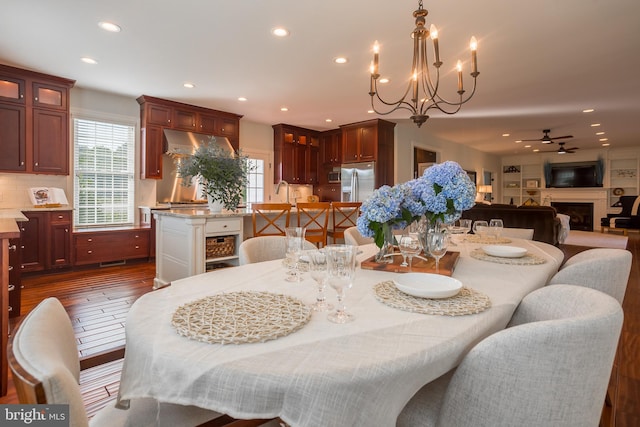 dining room with dark hardwood / wood-style flooring and ceiling fan with notable chandelier