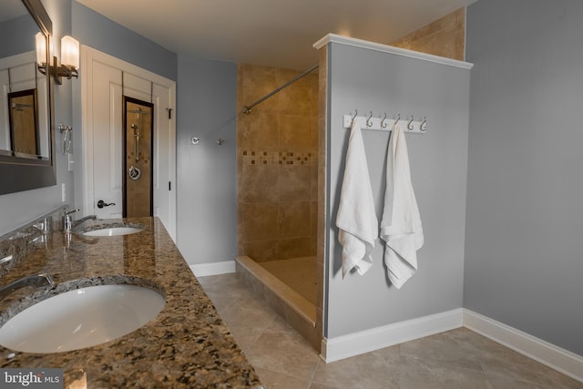 bathroom featuring tiled shower, tile patterned flooring, and double sink vanity