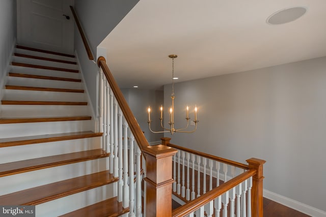 staircase featuring an inviting chandelier and hardwood / wood-style flooring