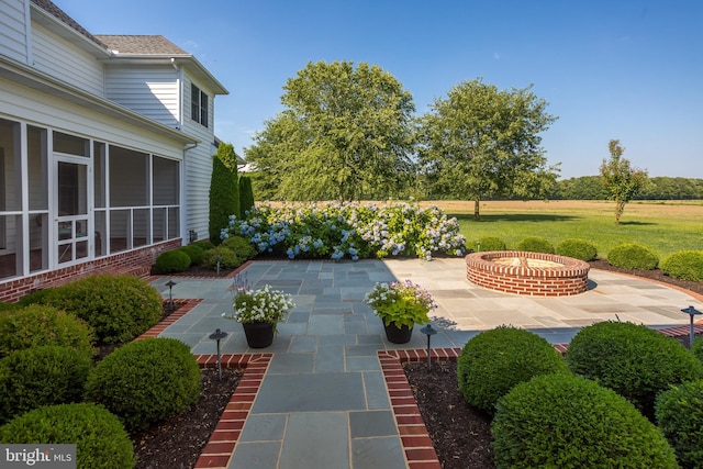 view of patio featuring a sunroom and a fire pit