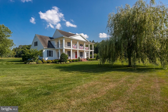 view of front facade with a balcony and a front lawn