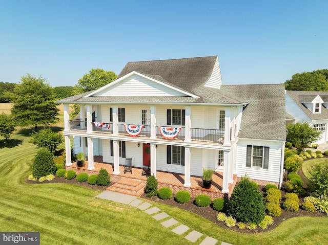 view of front of house featuring a balcony and a front lawn