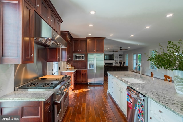 kitchen with appliances with stainless steel finishes, sink, light stone counters, dark hardwood / wood-style floors, and white cabinetry