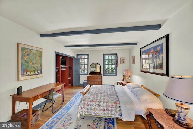 bedroom featuring beamed ceiling and wood finished floors