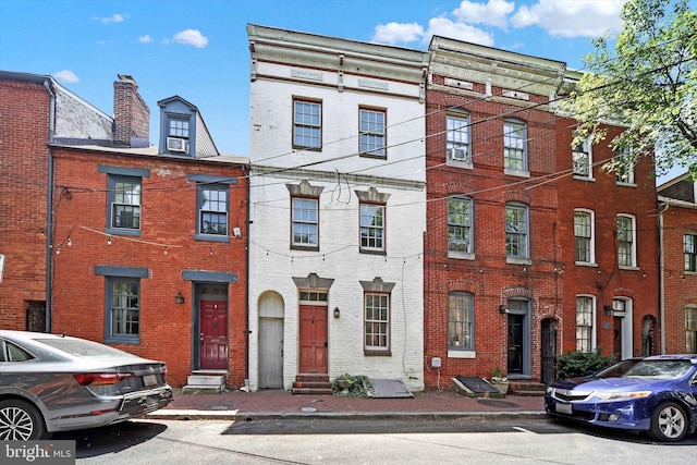 townhome / multi-family property with cooling unit, brick siding, and entry steps