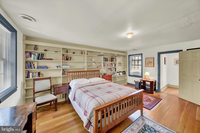 bedroom with visible vents, light wood-type flooring, and baseboards