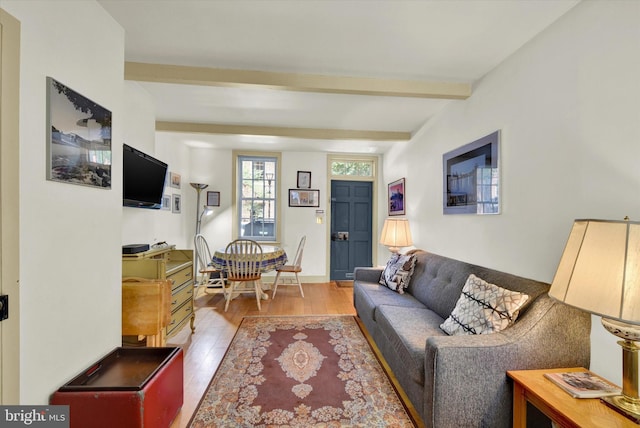 living area featuring beam ceiling and light wood-style flooring