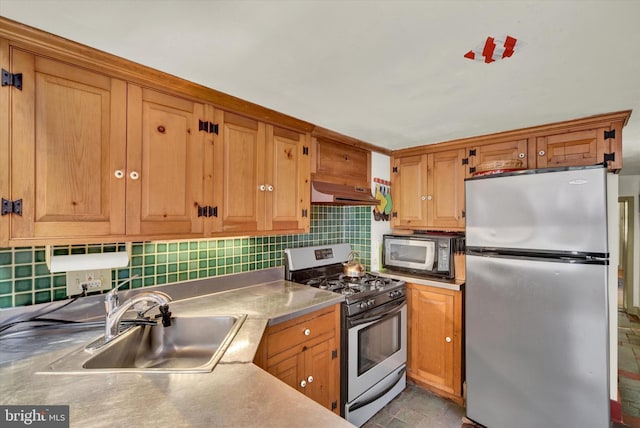 kitchen featuring backsplash, under cabinet range hood, brown cabinets, appliances with stainless steel finishes, and a sink