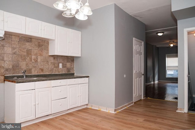 kitchen with decorative backsplash, light wood-type flooring, white cabinetry, and sink