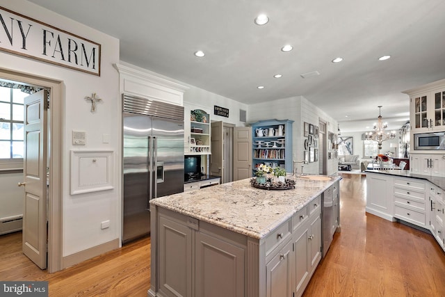 kitchen featuring built in appliances, a kitchen island, white cabinets, and a healthy amount of sunlight