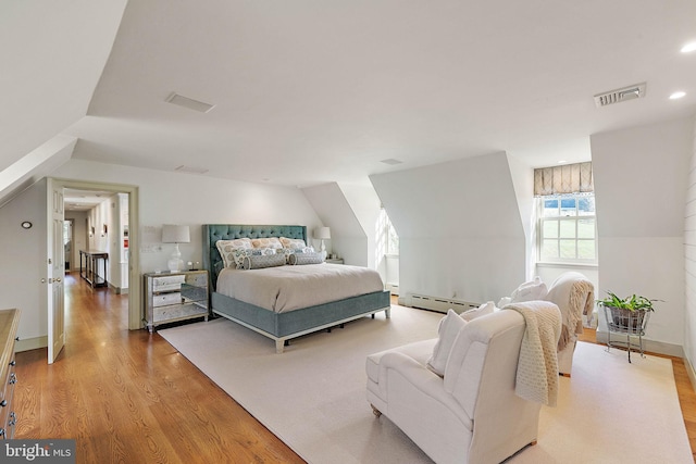 bedroom featuring a baseboard radiator, light hardwood / wood-style flooring, and lofted ceiling