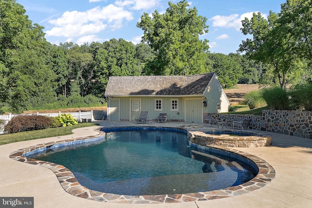 view of pool featuring an in ground hot tub, a patio, and an outdoor structure