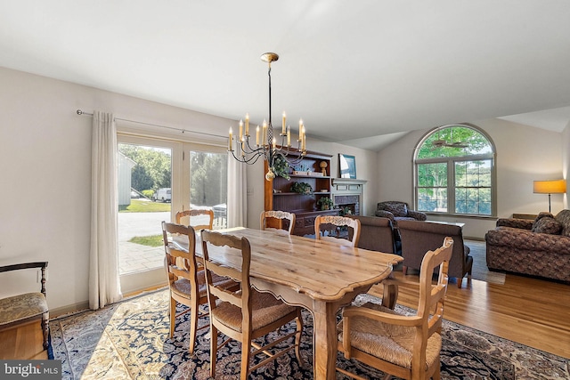 dining area featuring a chandelier, wood-type flooring, and lofted ceiling