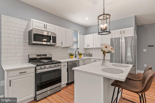 kitchen with white cabinets, a center island, appliances with stainless steel finishes, and tasteful backsplash