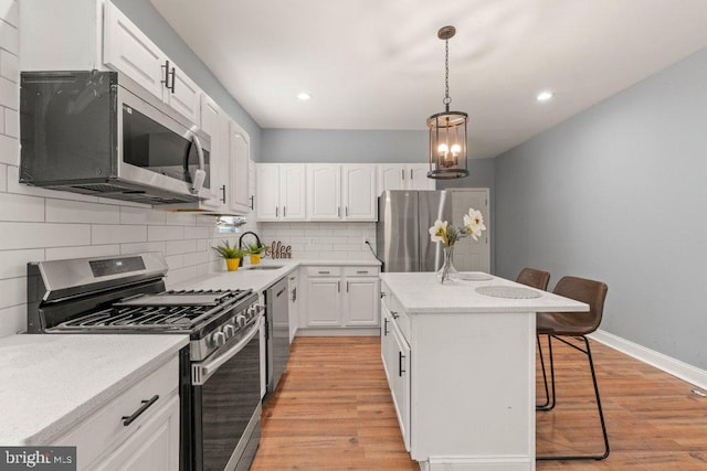 kitchen featuring a center island, white cabinets, decorative backsplash, a kitchen bar, and stainless steel appliances