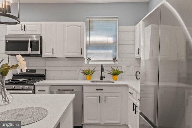 kitchen featuring stainless steel appliances, white cabinetry, tasteful backsplash, and sink