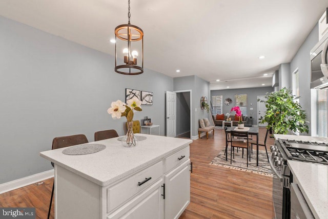 kitchen featuring pendant lighting, a breakfast bar, white cabinets, high end stove, and a kitchen island