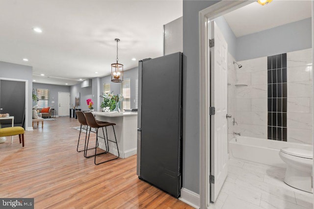 interior space with stainless steel fridge, a kitchen breakfast bar, light hardwood / wood-style floors, and hanging light fixtures