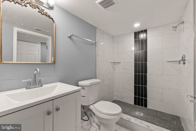 bathroom with a tile shower, vanity, and toilet