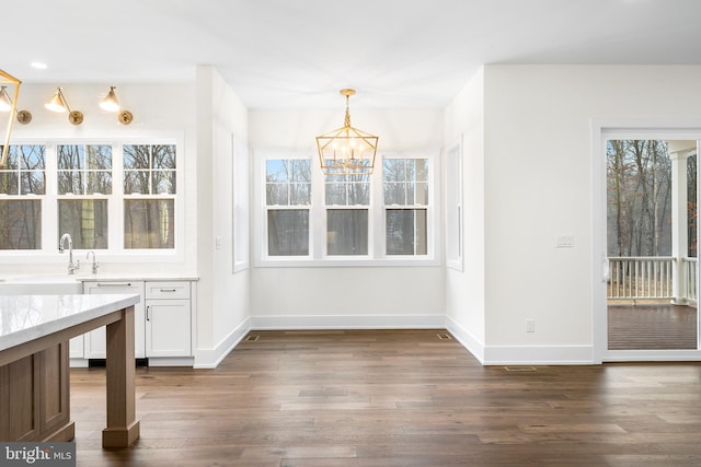 unfurnished dining area featuring a chandelier, dark wood-type flooring, and sink