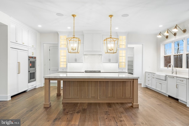 kitchen featuring white cabinetry, a center island, pendant lighting, and sink